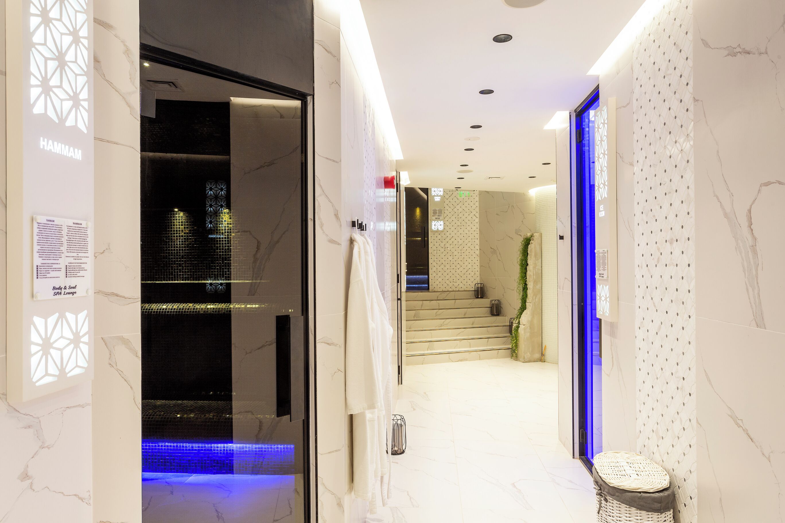 Un moderno vestíbulo de hotel con suelo de mármol, entrada de vidrio y una escalera que conduce a los pisos superiores.