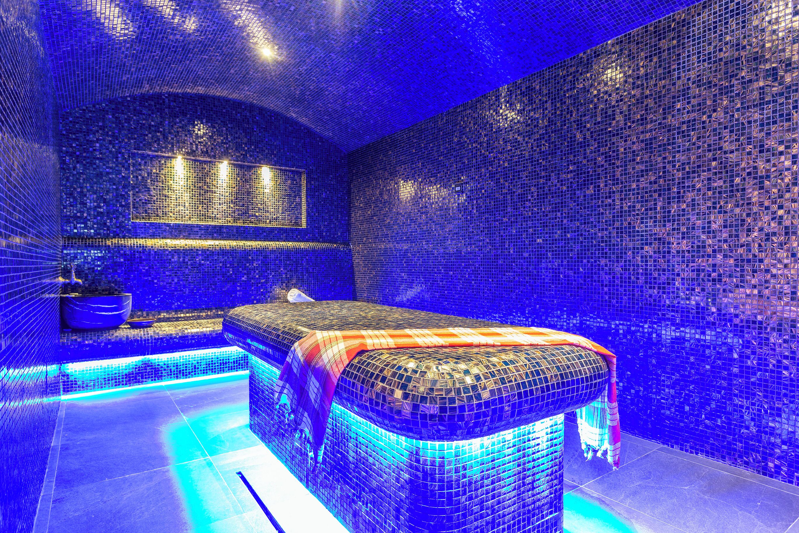 Ein Zimmer mit einem großen Bett, einer kleinen Sitzecke und einer Wand mit einem Mosaikmuster.