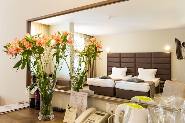 A hotel room with a bed, a TV, a telephone, and a vase with flowers. - Perelik hotel (Pamporovo)