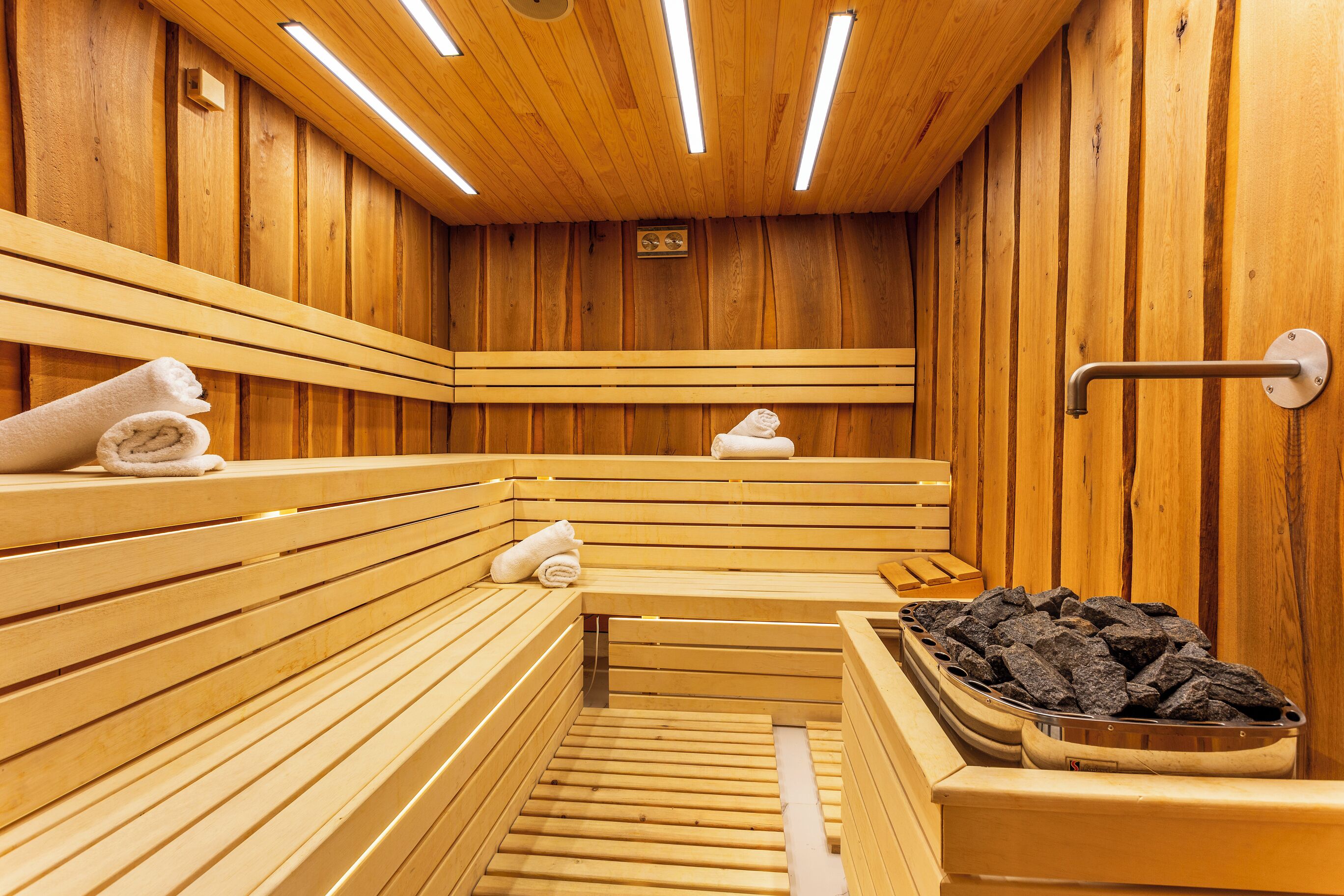 A wooden sauna with benches and a bench with towels.