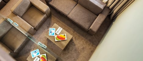 Un salon moderne avec un canapé d’angle, une table basse en verre et une petite table d’appoint.