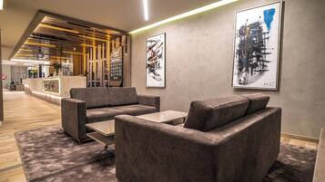 A modern lobby with a reception desk, grey sofas, and abstract art on the walls.