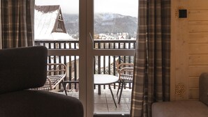 Quarto com vista para uma montanha nevada e um deck de madeira com móveis de vime.