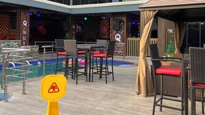 Un patio con piscina, mobiliario exterior y un edificio con el letrero 'NUTS Lounge & Suites'.