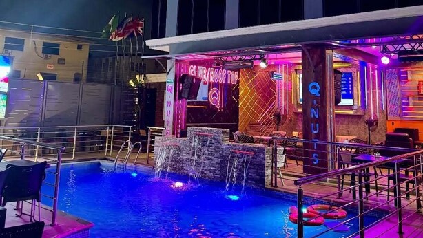 Zona de piscina en la azotea con bar y asientos, rodeada por una barandilla.