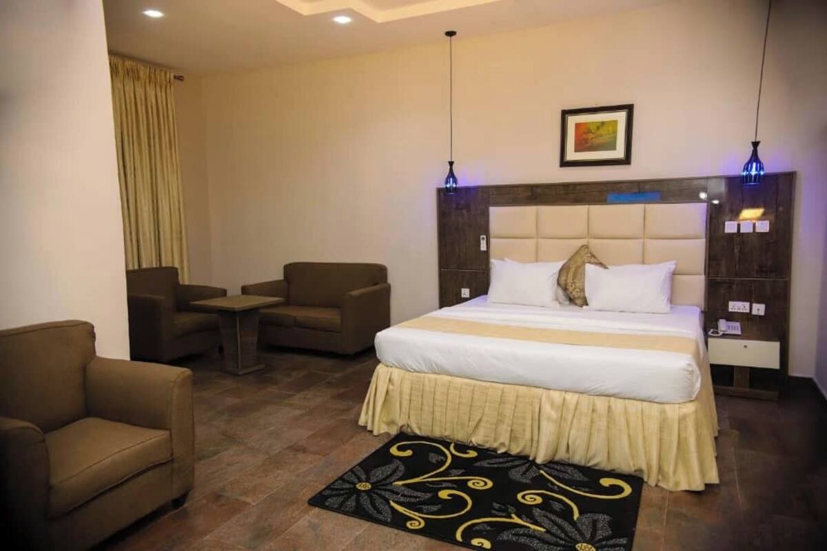 A hotel room with a large bed, two armchairs, a small table, and a decorative rug.
