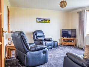A living room with two reclining chairs, a television, and a painting on the wall.
