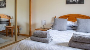 Une chambre à coucher avec un lit, une table de chevet, une lampe, un miroir et un tableau accroché au mur.
