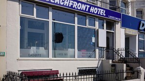 Hotel aan het strand met een opvallend blauw bord, grote ramen en een witte gevel.