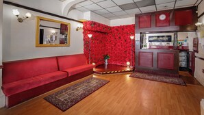 Een receptiegedeelte met een rode bank, een muur versierd met rode bloemen, een receptiebalie en een klok.