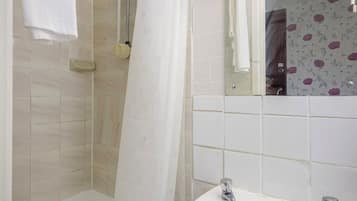 A bathroom with a shower, a sink, and a mirror.