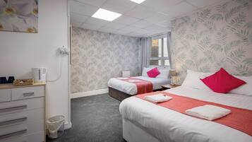 A hotel room with two beds, a desk, and a window.