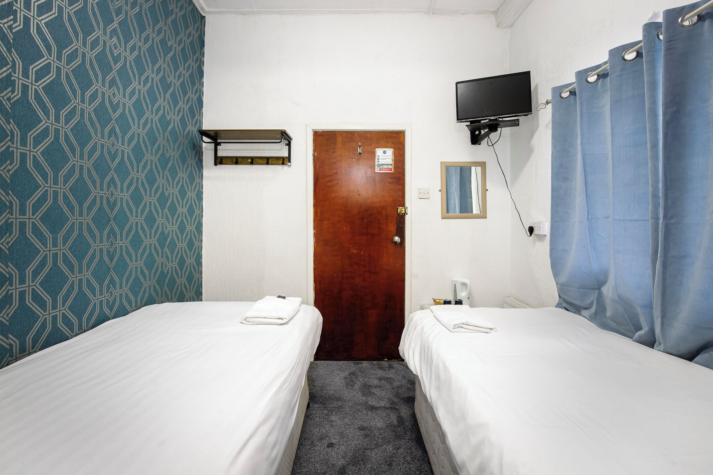 Habitación de hotel con dos camas, un televisor sobre la puerta y una cortina de ducha.