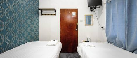 Habitación de hotel con dos camas, un televisor sobre la puerta y una cortina de ducha.