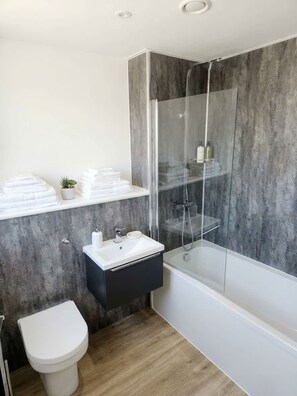 A modern bathroom with a glass-enclosed shower, a white sink, and a toilet.