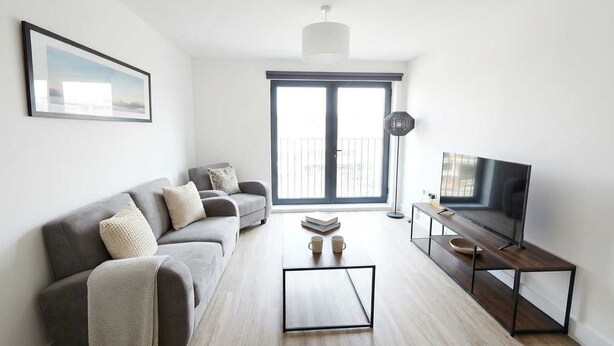 Un salon moderne avec un canapé gris, une table basse et un meuble pour la télévision.