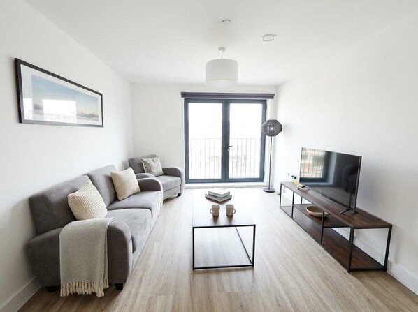 A modern living room with a grey sofa, a coffee table, and a TV stand.