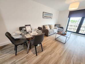 A modern living room with a dining table, two sofas, a coffee table, and a large window.