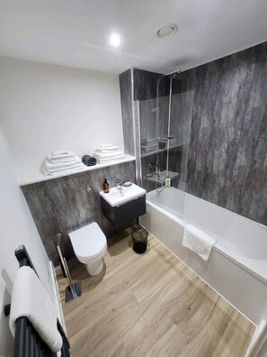 Une salle de bain moderne équipée de toilettes, d’un lavabo et d’une baignoire.