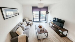Un salon moderne avec un canapé, une table basse et un téléviseur.