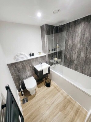 A modern bathroom with a bathtub, a toilet, and a sink.