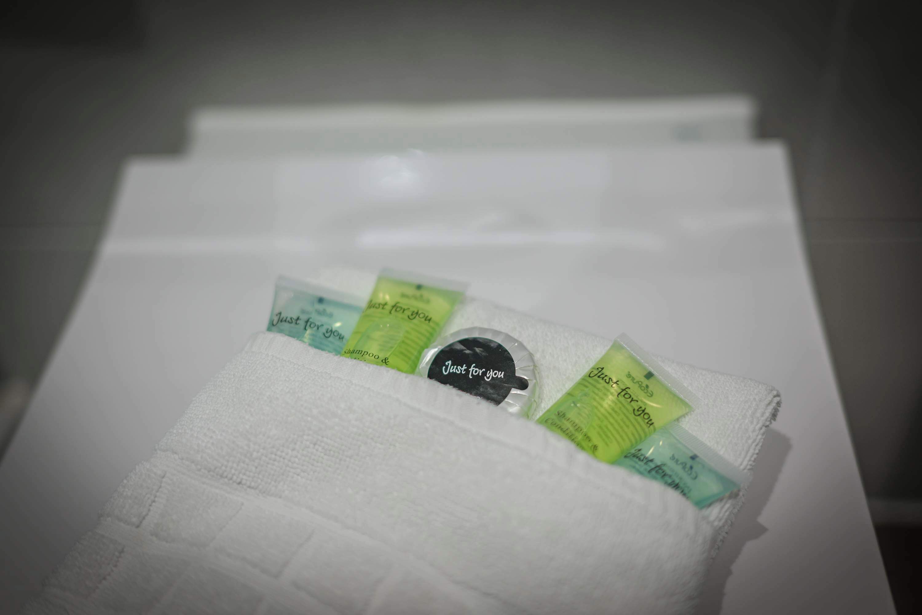 Ein weißes Handtuch mit mehreren kleinen Packungen, beschriftet mit „Nur für Sie“, auf einer weißen Oberfläche.