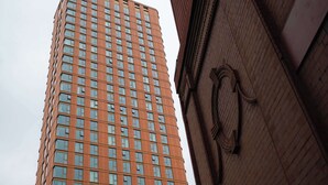 Un immeuble de grande hauteur, doté d’une façade en briques et d’une série de fenêtres disposées en réseau.
