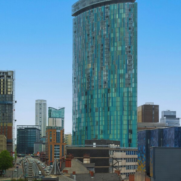A modern high-rise building with a glass facade, surrounded by other buildings and a busy street.