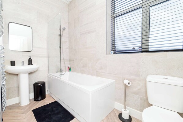 Un baño moderno con lavamanos blanco, bañera y retrete.