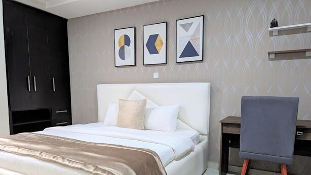 A bedroom with a bed, a desk, and a chair. There are three framed artworks on the wall. - La Topik Hotel and Suites (Ota)