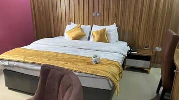 Habitación de hotel con cama, mesita de noche, una silla y pared de madera.