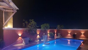 A swimming pool with a blue hue, surrounded by potted plants and a low wall with integrated lighting. - La Topik Hotel and Suites (Ota)