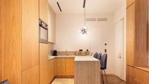 Une cuisine moderne avec des meubles en bois, un îlot central, des tabourets de bar et un luminaire suspendu.