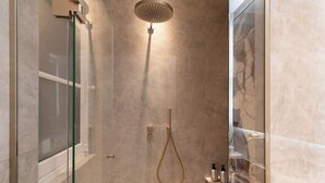 Une douche moderne dotée d’un pommeau de douche à main et d’un panneau de commande fixé au mur.