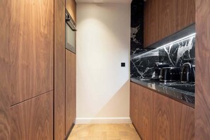 A modern kitchen with wooden cabinets, a marble countertop, and a built-in stove.