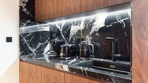 A modern kitchen with a black marble countertop, wooden cabinets, and stainless steel appliances. - ONIRI - Serviced 2-BR/2BA - Louvre Richelieu II (Paris)