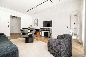 A modern living room with a fireplace, a dining area, and a sofa.