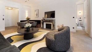 A modern living room with a fireplace, a flat-screen TV, and a round coffee table. - ONIRI - Serviced 2-BR/2BA - Louvre Richelieu II (Paris)