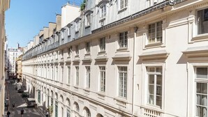 A row of white buildings with uniform architecture, large windows, and a clear street in front.