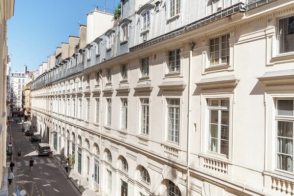 A row of white buildings with uniform architecture, large windows, and a clear street in front.