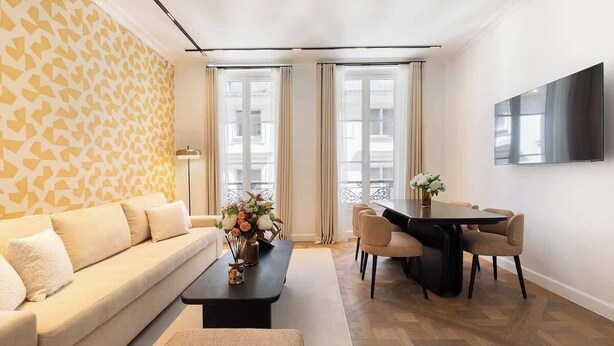 A modern living room with a sofa, coffee table, and dining area with chairs.