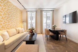 A modern living room with a sofa, coffee table, and dining area with chairs.
