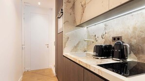 A modern kitchen with a marble backsplash, a built-in oven, and a black countertop.