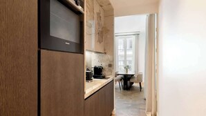 A modern kitchen with dark wood cabinetry, a built-in oven, and a coffee machine.