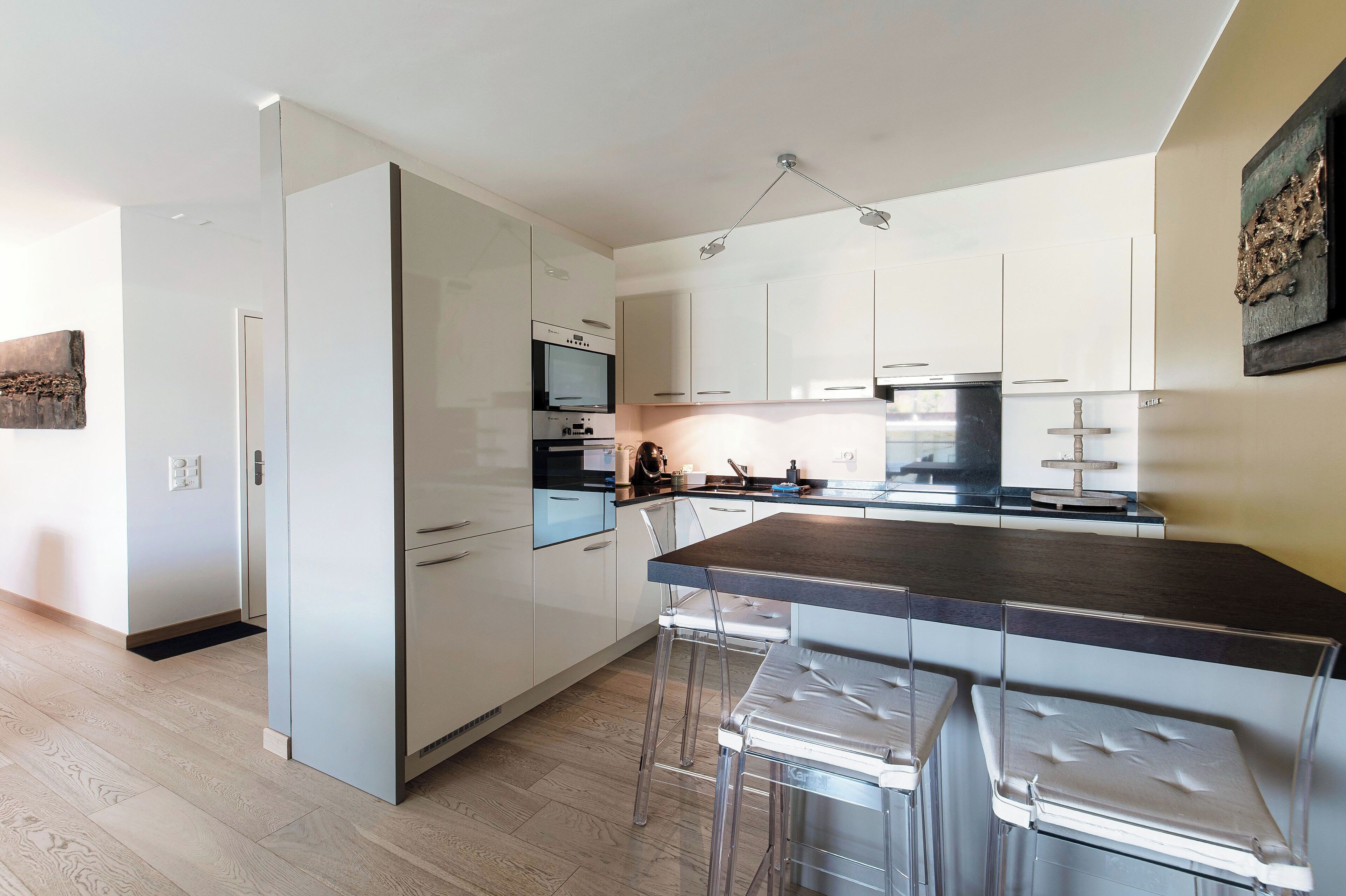 A modern kitchen with white cabinets, stainless steel appliances, and a central island with bar stools.