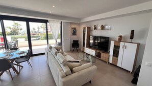 A modern living room with a sofa, TV, and dining area with a table and chairs. - 2 bedroom apartment in torrox costa (Torrox Costa)