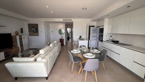 A modern living room with a sofa, TV, and dining area with chairs and a table. - 2 bedroom apartment in torrox costa (Torrox Costa)