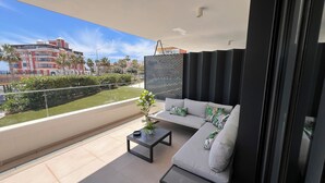 A balcony with a sofa, a small table, and a potted plant. - 2 bedroom apartment in torrox costa (Torrox Costa)