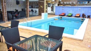 A pool area with a rectangular pool, black wicker chairs, and a glass table. - Britannia Hotel and Suites (Lagos)
