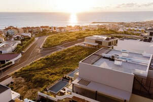 Un área residencial costera con edificios modernos, una calle y vista al mar.